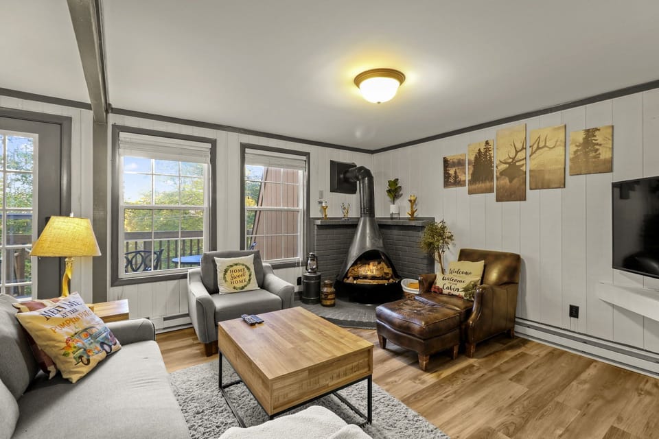 Freshly decorated living room includes group seating, fireplace, smart TV, sleeper sofa for 1, blanket basket