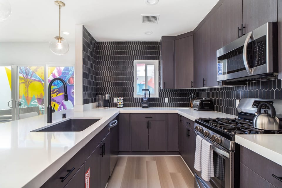 This kitchen is fit for any chef... stainless steel appliances and white quartz waterfall counters