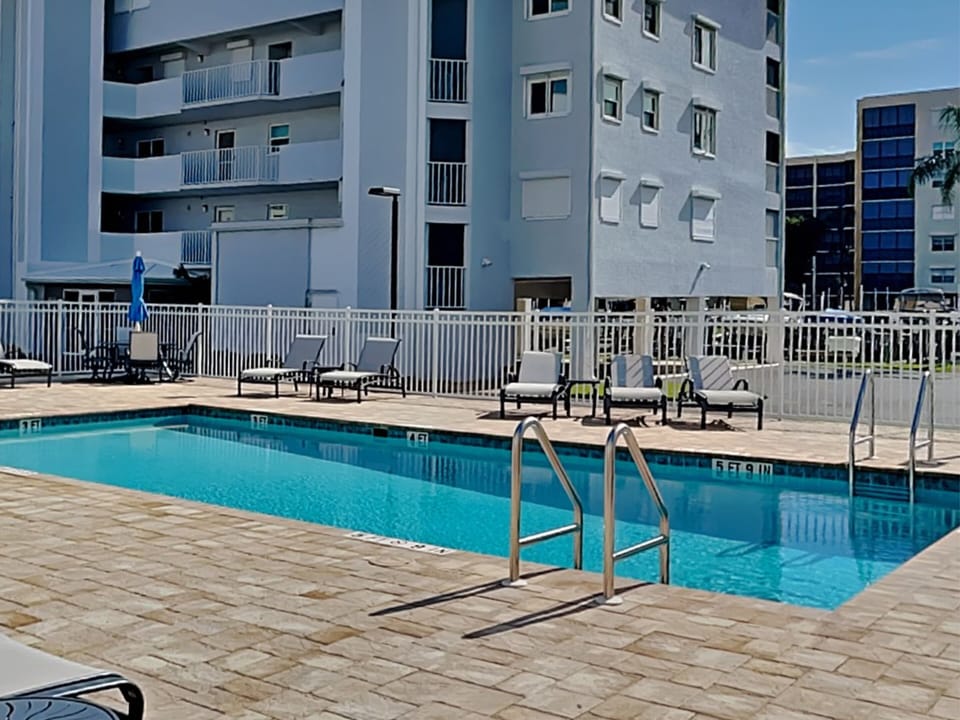 Community Pool with Sun Loungers + Dining Tables