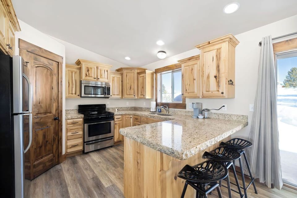 Fully stocked kitchen leading out to a partially covered deck with BBQ, outdoor dining table, party lights, fire ring and hot tub