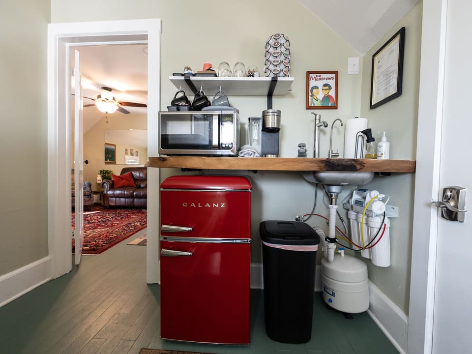 Micro kitchen features Keurig coffee maker, plates and cutlery.