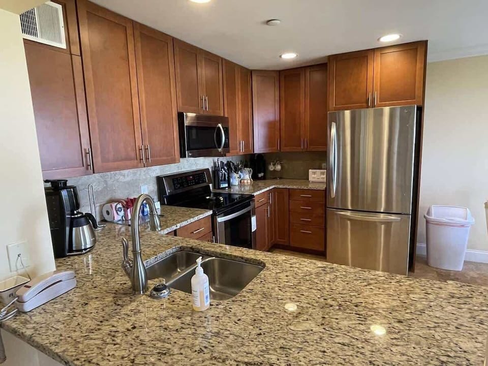 A fully equipped kitchen featuring rich wood cabinetry and granite countertops.

