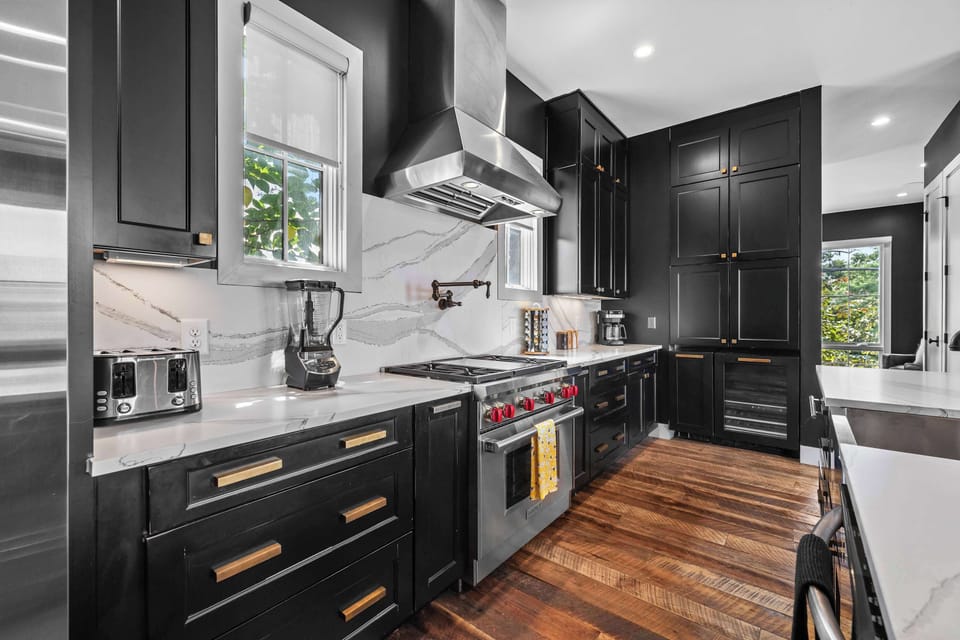 Spacious and inviting living room featuring comfortable sectional seating, exposed brick walls, a Smart TV, and an open-concept layout that flows seamlessly into the kitchen and dining area.
