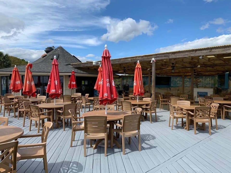 A wide communal deck featuring several umbrella-shaded tables