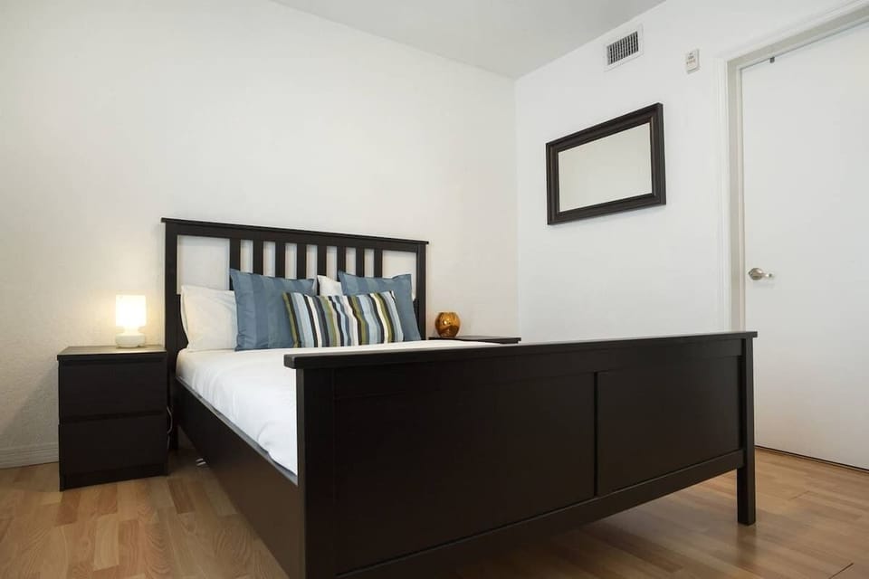 Sleep soundly in this minimalist Airbnb bedroom with cozy pillows, warm lighting, and a calming vibe.


