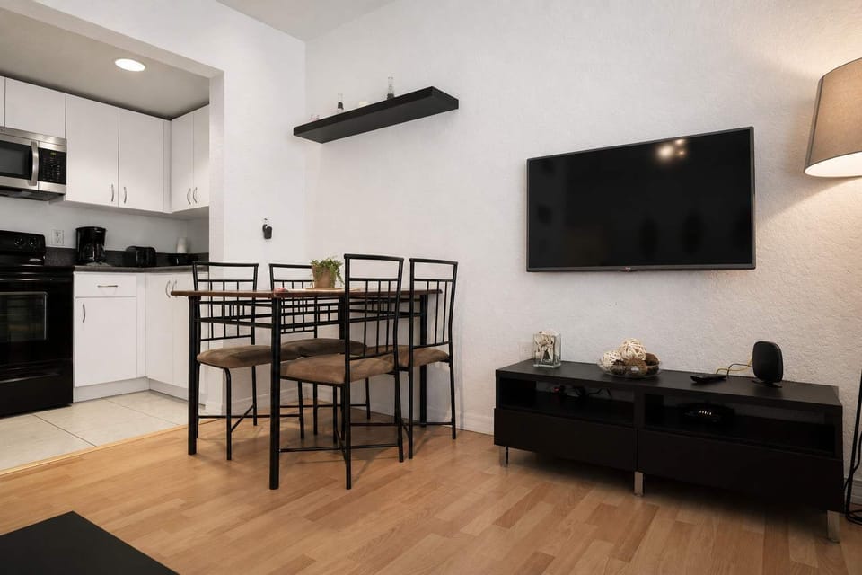 Enjoy meals and movie nights in this cozy Airbnb with open kitchen, dining space, and entertainment setup.