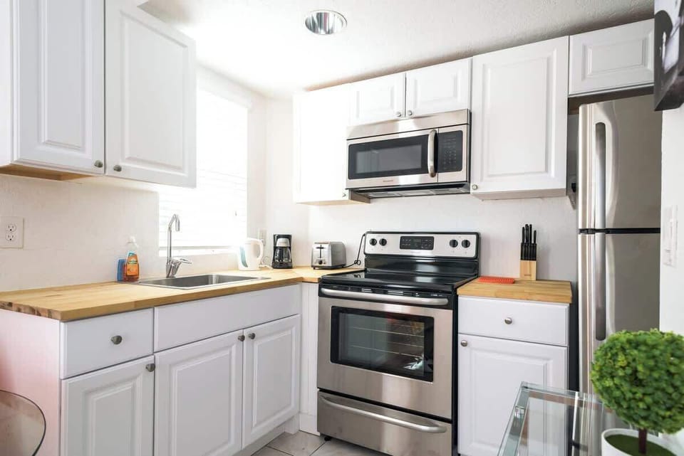 Enjoy cooking in this airy Airbnb kitchen with stainless steel appliances, wood countertops, and a sunny window view.