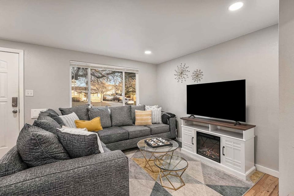 - Relax in this cozy living room with a modern sectional, warm accent pillows, & fireplace TV console
- Large window brings in natural light while recessed ceiling lights brighten the space
- Stylish decor & plush rug create a warm & inviting setting
