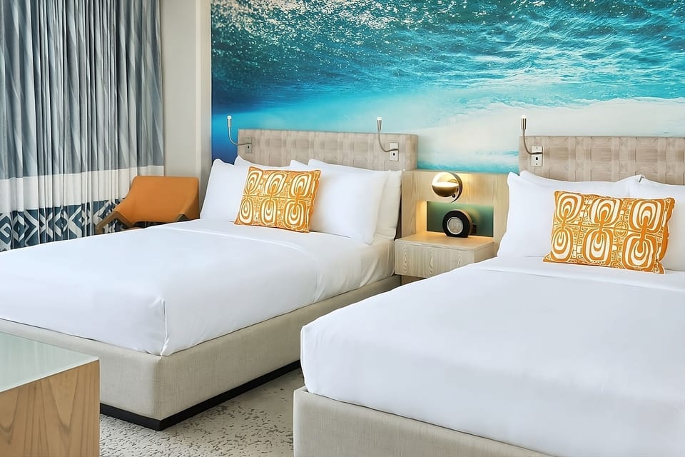 Sink into crisp beds beneath a dreamy ocean-wave mural.