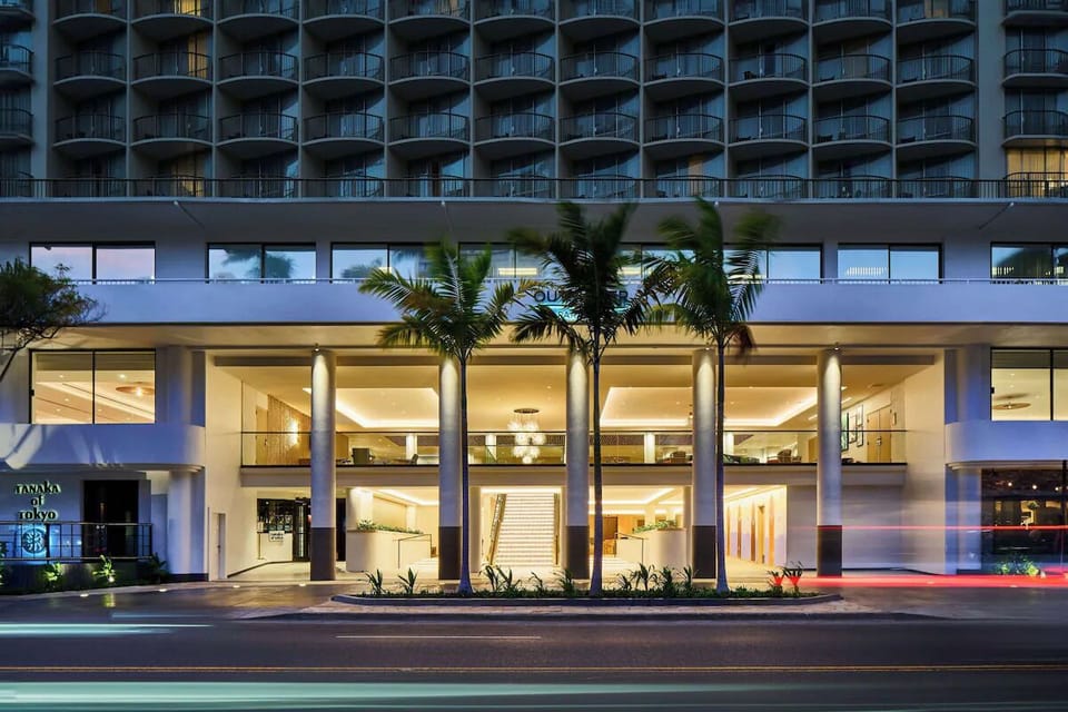 Arrive to a glowing, resort-style entrance framed by palms.