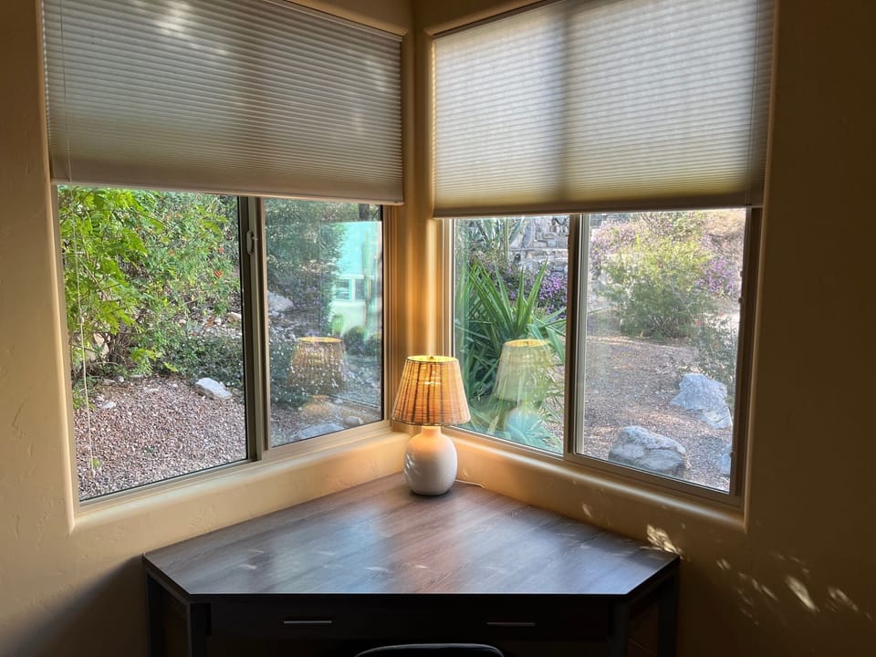 Close up of dimmable desk lamp with blinds partially up.