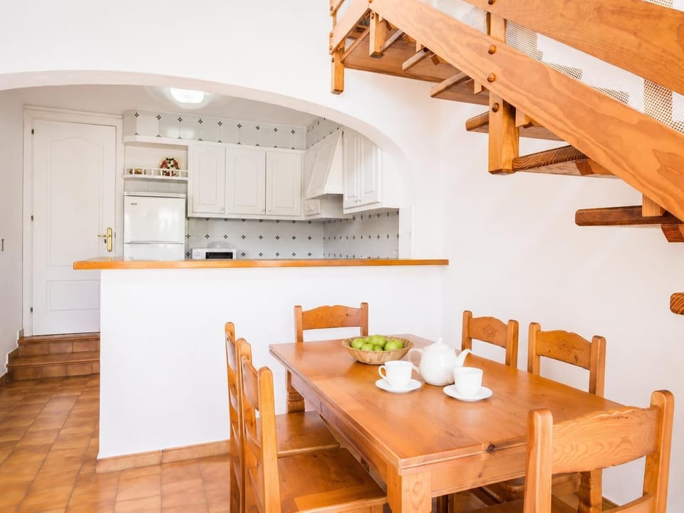 Open-plan living room with sofas, dining area, kitchen, ornamental fireplace, A/C, WiFi internet, and satellite TV