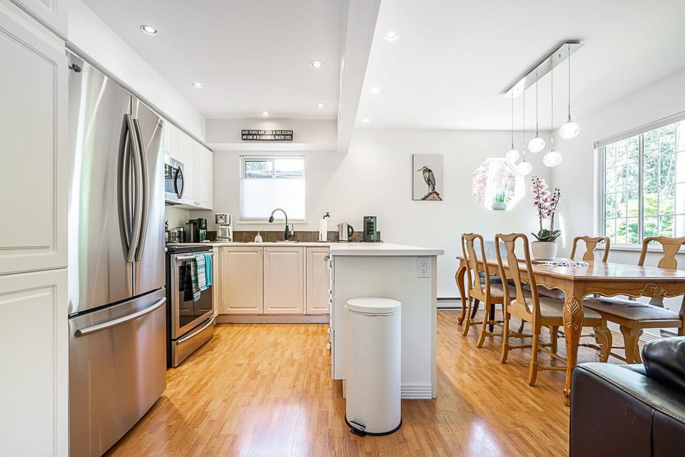 White kitchen with stainless steel fridge, stove and dishwasher.