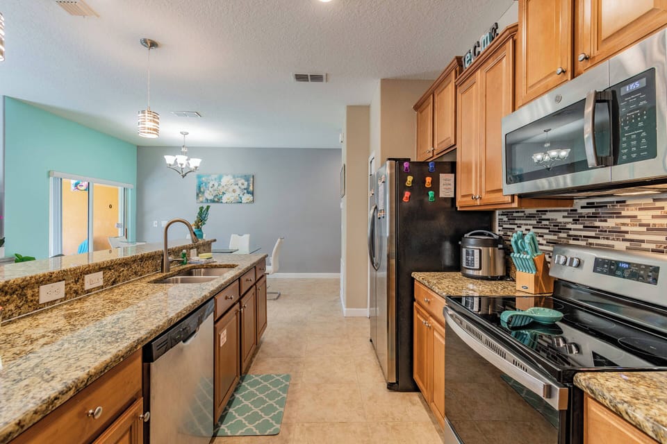 Experience the charm of this stylish kitchen, featuring rich wooden cabinetry and sleek granite countertops. Modern appliances and a vibrant teal accent wall make it a welcoming space for creating your favorite meals.