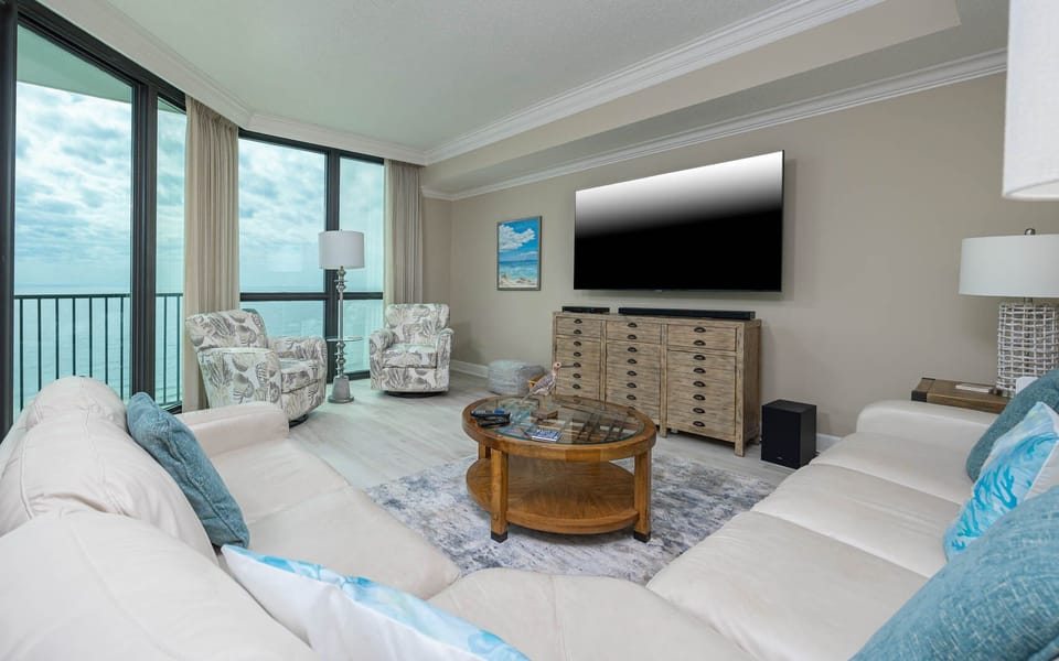 Relax in the inviting living area with plush seating, a large TV, and stunning views through expansive windows