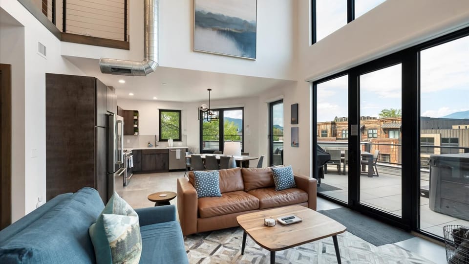 Open concept living room with gas fireplace and SmartTV, dining area, and kitchen with wrap around balcony and hot tub