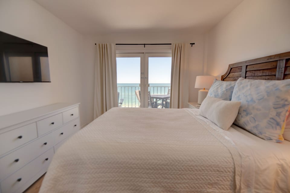 Primary bedroom featuring a queen bed with doors leading to the balcony. 