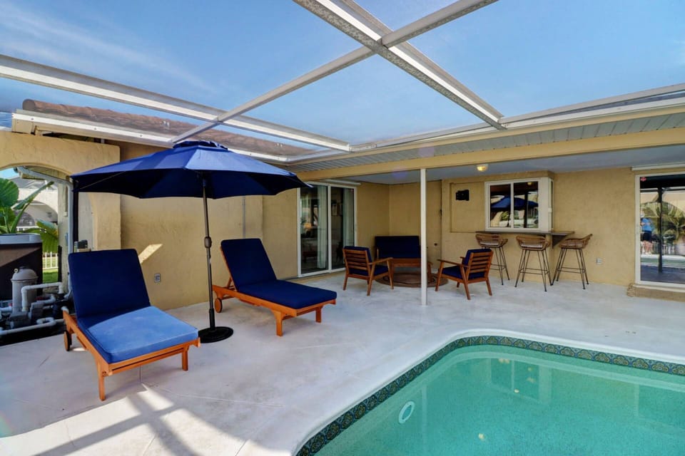 The large pool deck features resort style furnishings, including 2 sun lounges with umbrella for shade.