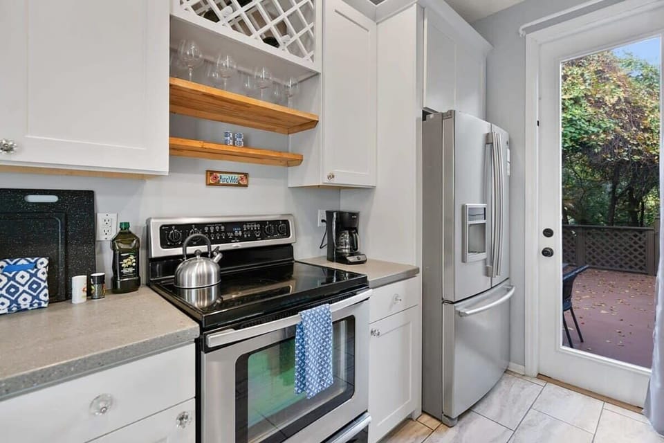 Kitchen overlooks a back patio with additional dining and fire pit (guests must provide their own firewood)