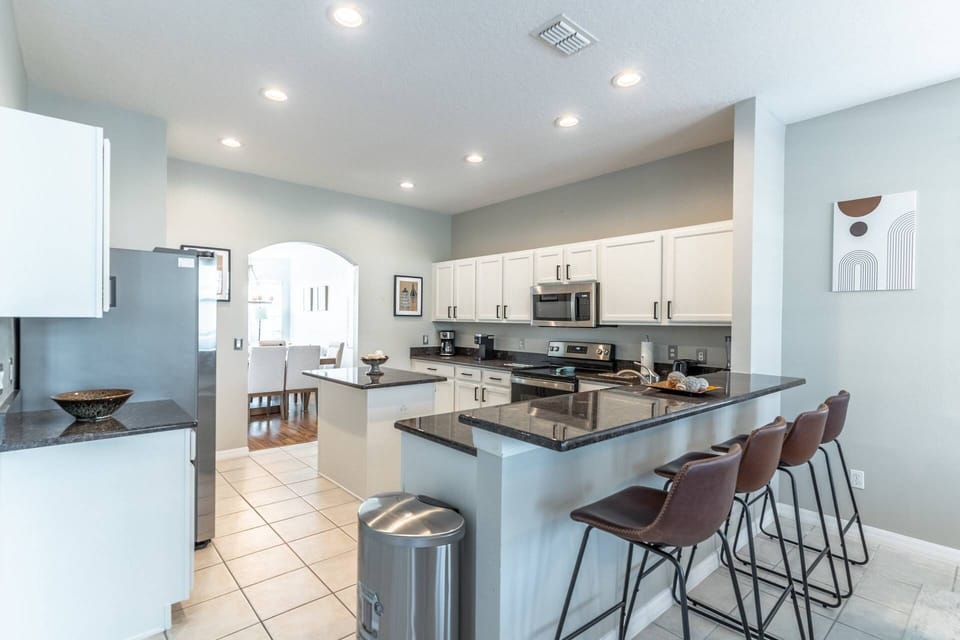Bright and modern kitchen with stainless steel appliances and bar seating for 4