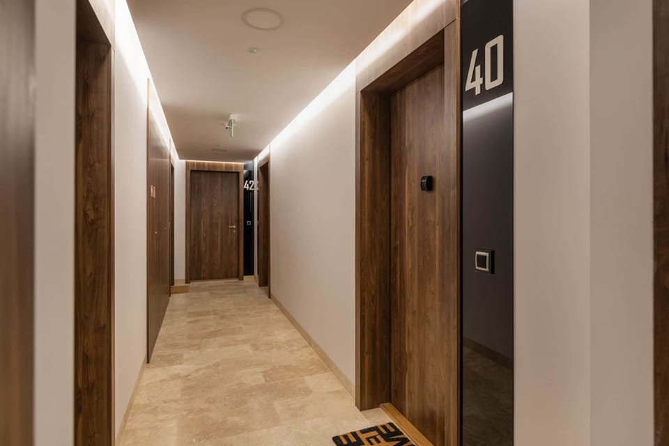A hallway with wooden doors, lighting, and a sleek, contemporary design. Creates a warm, inviting entryway to the living space.