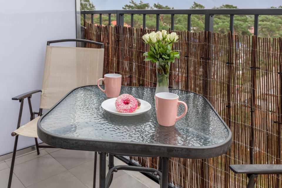 A small balcony table set with two cups, providing a nice spot to enjoy a morning coffee, with bamboo fencing for privacy.