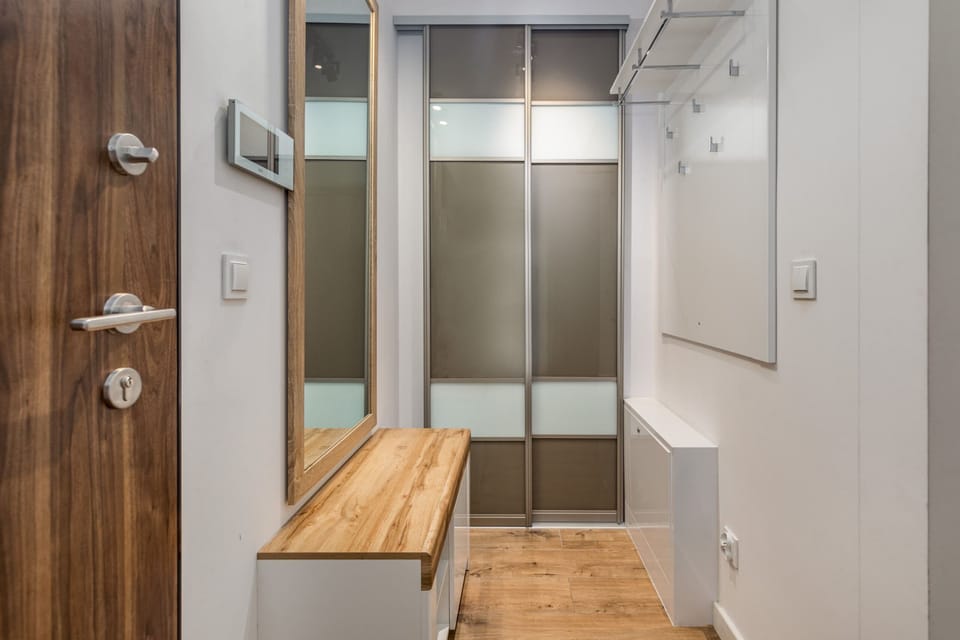 A small hallway with a sliding mirrored wardrobe, perfect for storing coats and shoes. It’s well-lit and maximizes space efficiency.