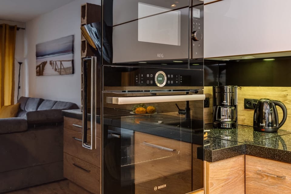 An oven built into the kitchen cabinetry, sleek and modern, with functions for reheating and multi-level cooking. It blends perfectly with the rest of the kitchen design.

