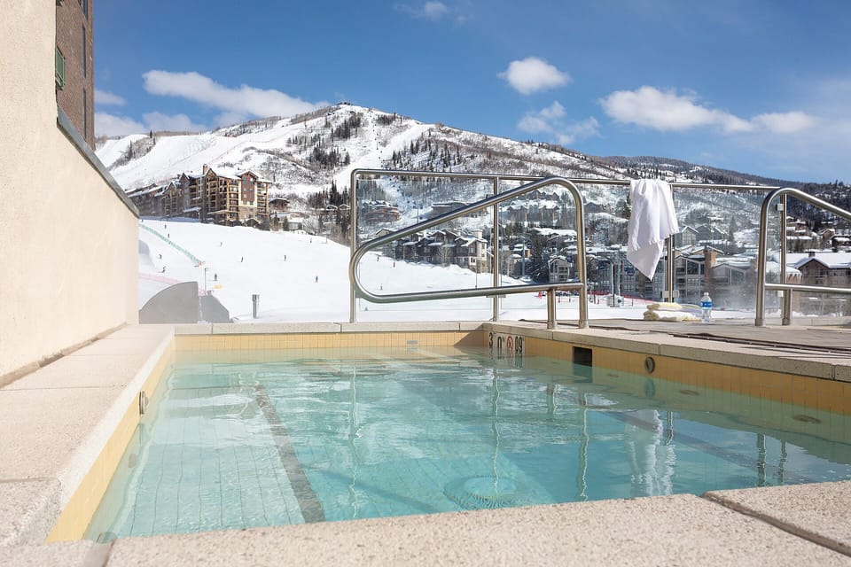 An outdoor pool overlooks pristine ski slopes and snow-covered peaks at this mountain resort property, offering a scenic winter escape.