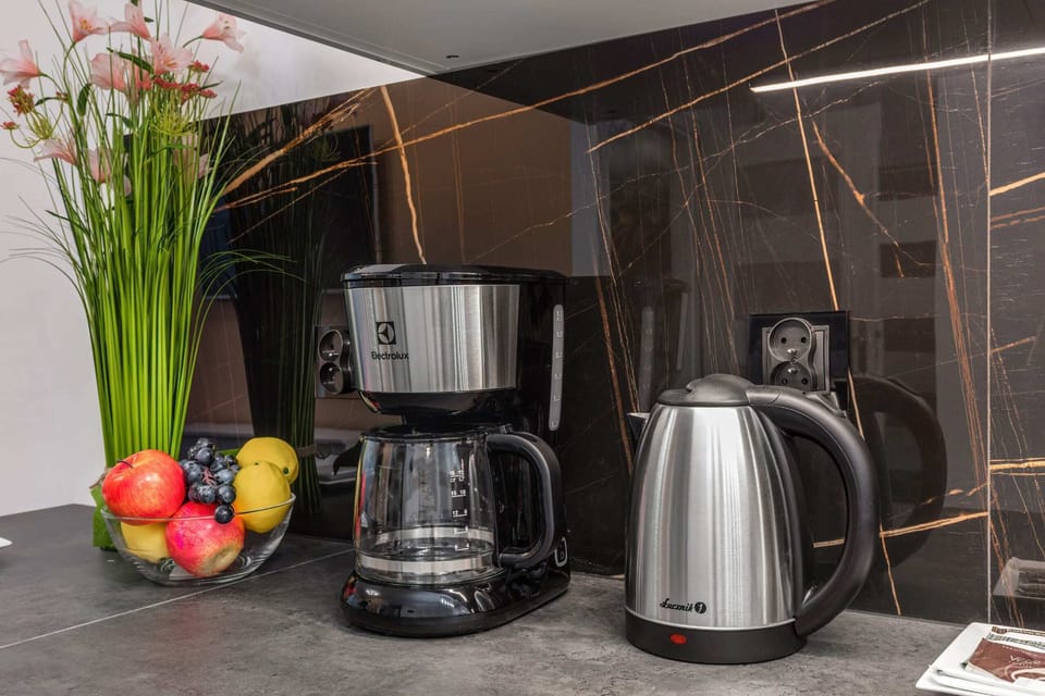 A kitchen countertop adorned with a coffee maker, electric kettle, and a vase of fresh flowers, creating a welcoming atmosphere.

