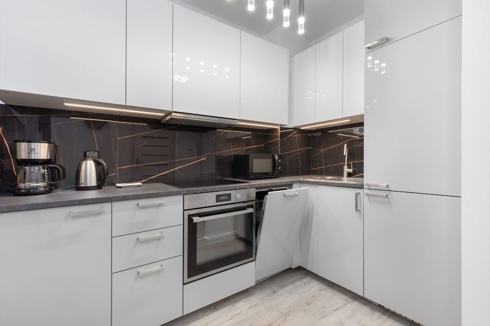 A contemporary kitchen with glossy white cabinetry, built-in appliances, and a minimalist design.
