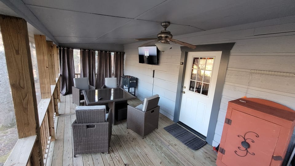 Screened in covered back porch area. Table with seating for 4 & 50" TV
