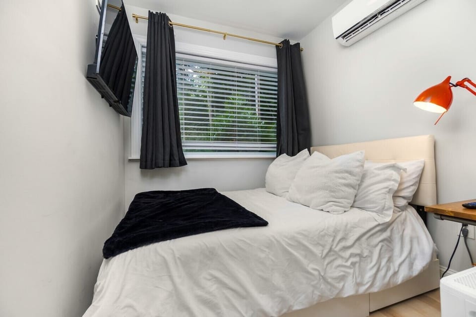 A cozy, private bedroom with plush bedding, a TV, individual climate control, and peaceful views of the surrounding greenery.