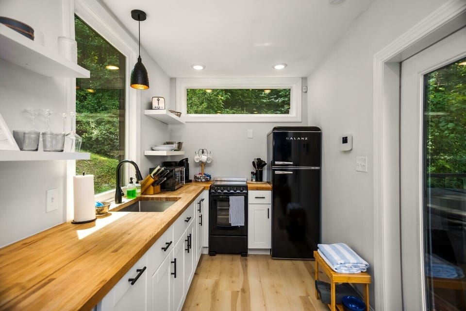 The efficient kitchen offers full-size appliances and plenty of prep space, with direct access to the deck and wooded surroundings.