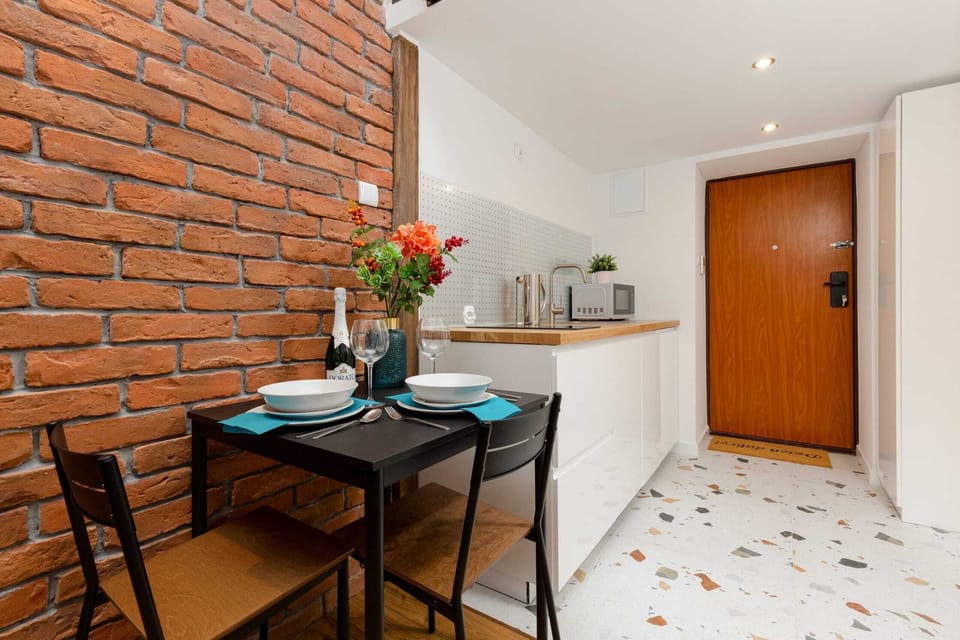 A compact dining area with a table set for two, brightened by fresh flowers and surrounded by stylish decor.
