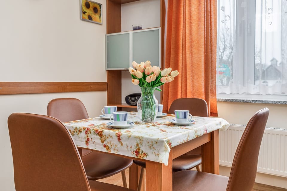 The dining area, set with a table and four chairs, is styled simply with fresh flowers. A cozy, homey spot for meals or work.