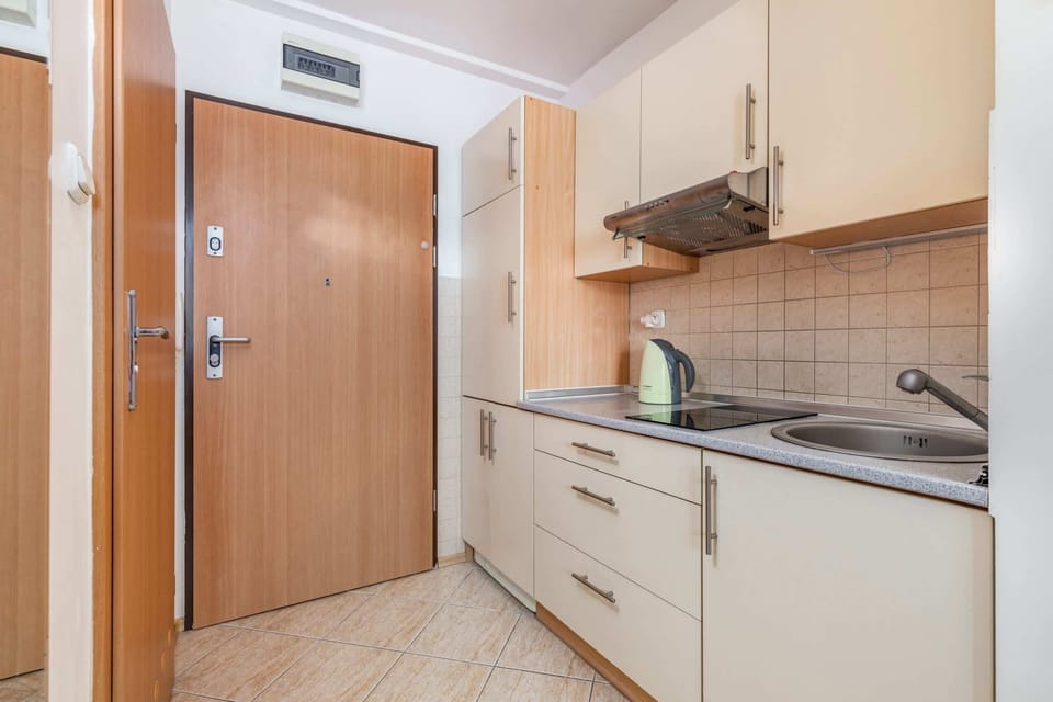 A compact, functional kitchen with light-colored cabinets and essential appliances, perfect for preparing meals in a cozy space.