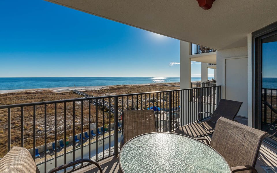 Balcony view showcasing the tranquil gulf waters and beach, with comfortable seating around a glass-top table
