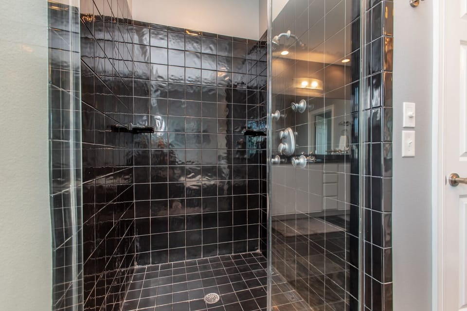 Sleek black tile and a spacious walk-in design create a modern, spa-like retreat where you can truly unwind under the rain showerhead.