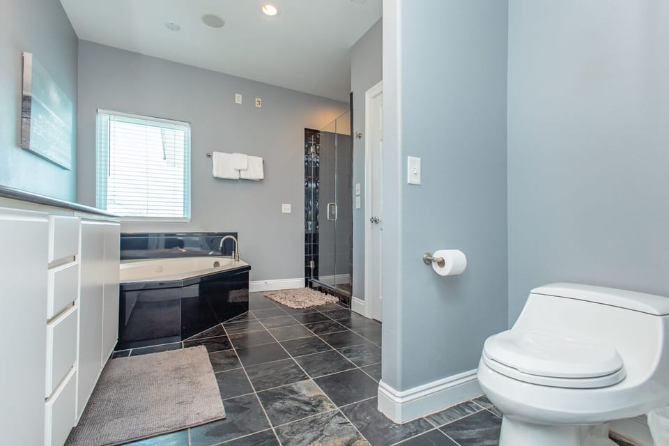 Luxurious retreat with a soaking tub and sleek walk-in shower. Glossy tile floors and natural light make this bathroom feel like your own private spa.
