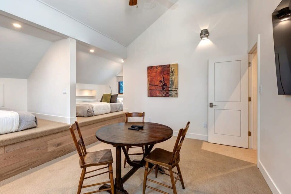 Third bedroom with two comfortable queen-size beds, closet with sliding mirror doors, table with seating for 3, and a large flat-screen TV