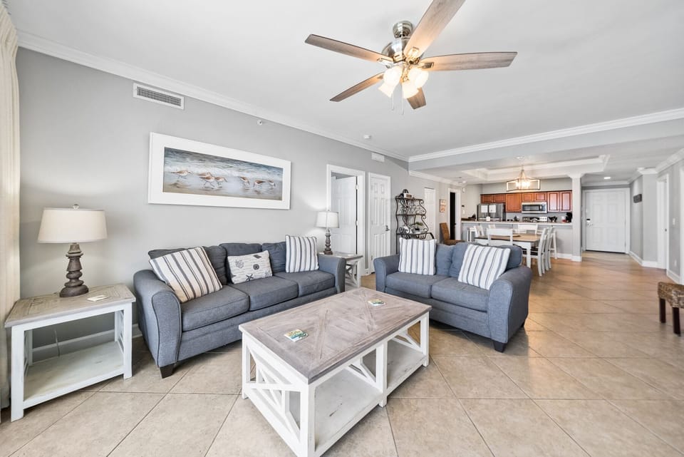 Relax in your bright, airy living space featuring comfortable seating and coastal decor, seamlessly connecting to your fully-equipped kitchen.
