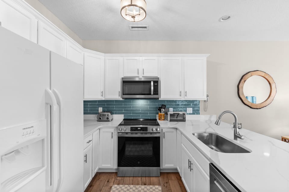 Your fully-equipped kitchen awaits with pristine counters, stainless appliances, and charming blue tile—perfect for whipping up morning coffee or full homemade meals during your stay.