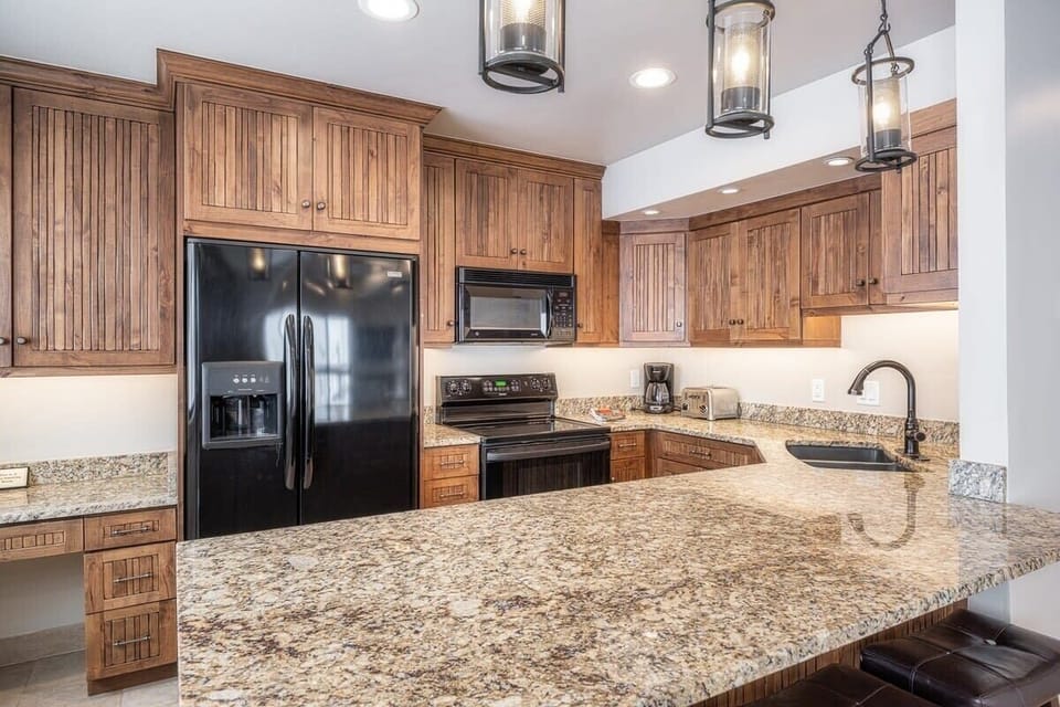 Spacious fully-equipped kitchen with granite countertop and bar stool seating