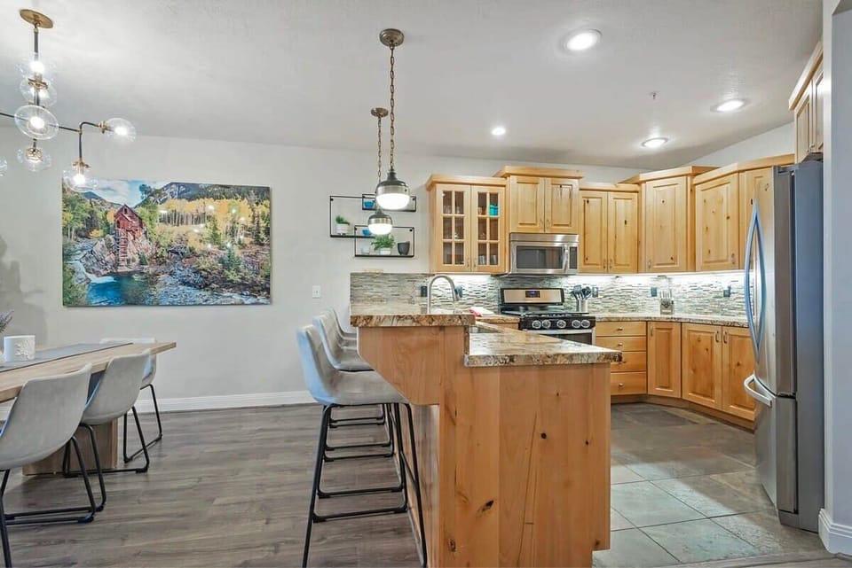 The fully-equipped kitchen boasts high-quality stainless steel appliances, beautiful granite countertops, and breakfast bar seating for four.
