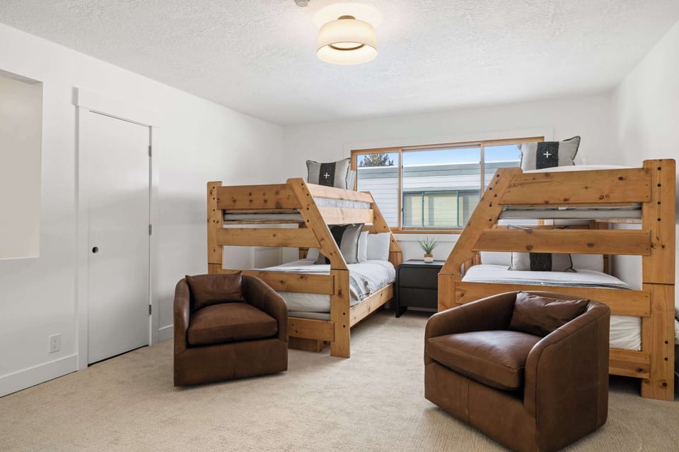 Loft bedroom with two twin over queen size bunk beds, a flat-screen TV, and a lounge seating area