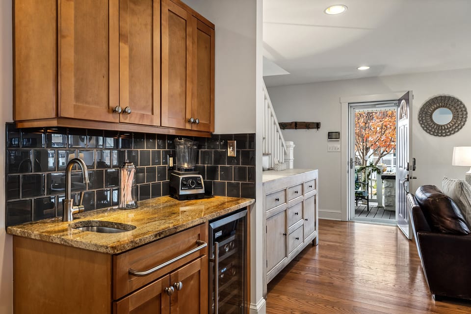 kitchen view to front door with bar sink, wine refrigerator.