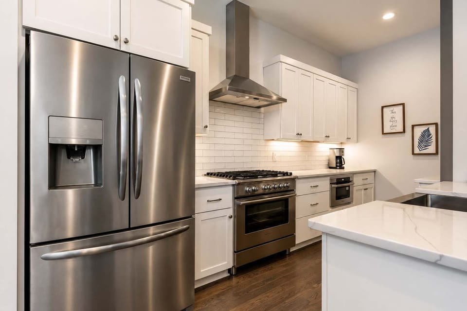 Bright and modern kitchen featuring sleek white cabinetry, stainless steel appliances, subway tile backsplash, and elegant quartz countertops.