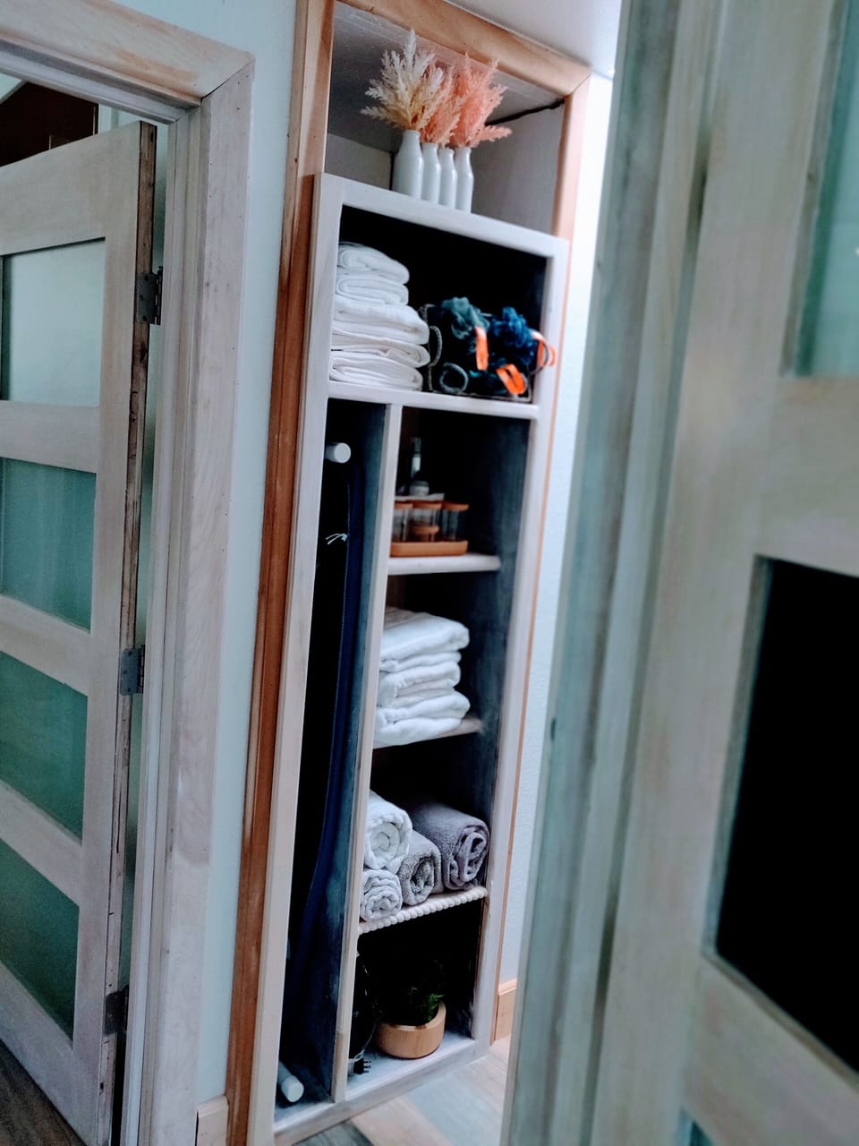 Hallway closet with towels, toiletries, first aid kit, ironing items.