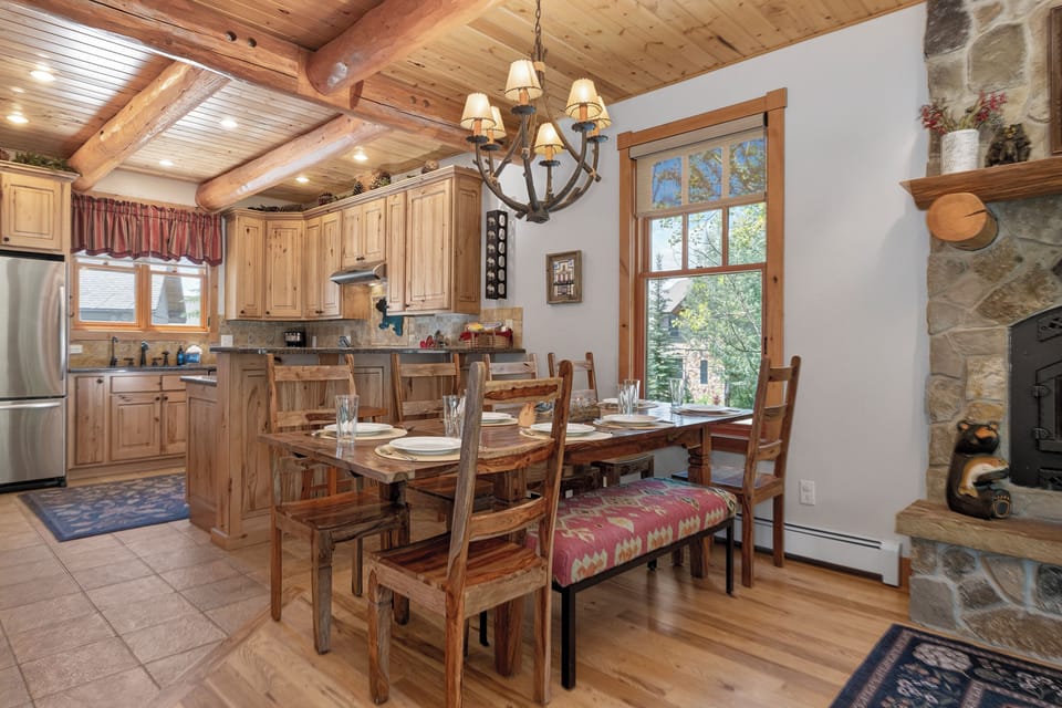 Step into your cozy mountain retreat where rustic warmth meets modern comfort. Gather around the handcrafted dining table beneath vaulted wood-beamed ceilings, while natural light streams through tall windows framing serene forest views.